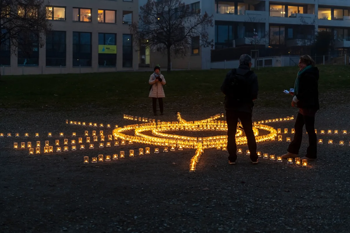 Ein Lichtermeer aus Kerzen, dahinter stehen Menschen und schauen andächtig.